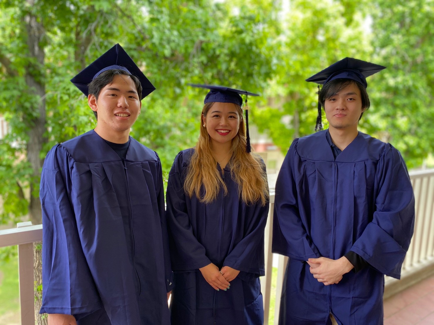 Rikiya poses in his cap and gown alongside two friends for his graduation from Merced City College.