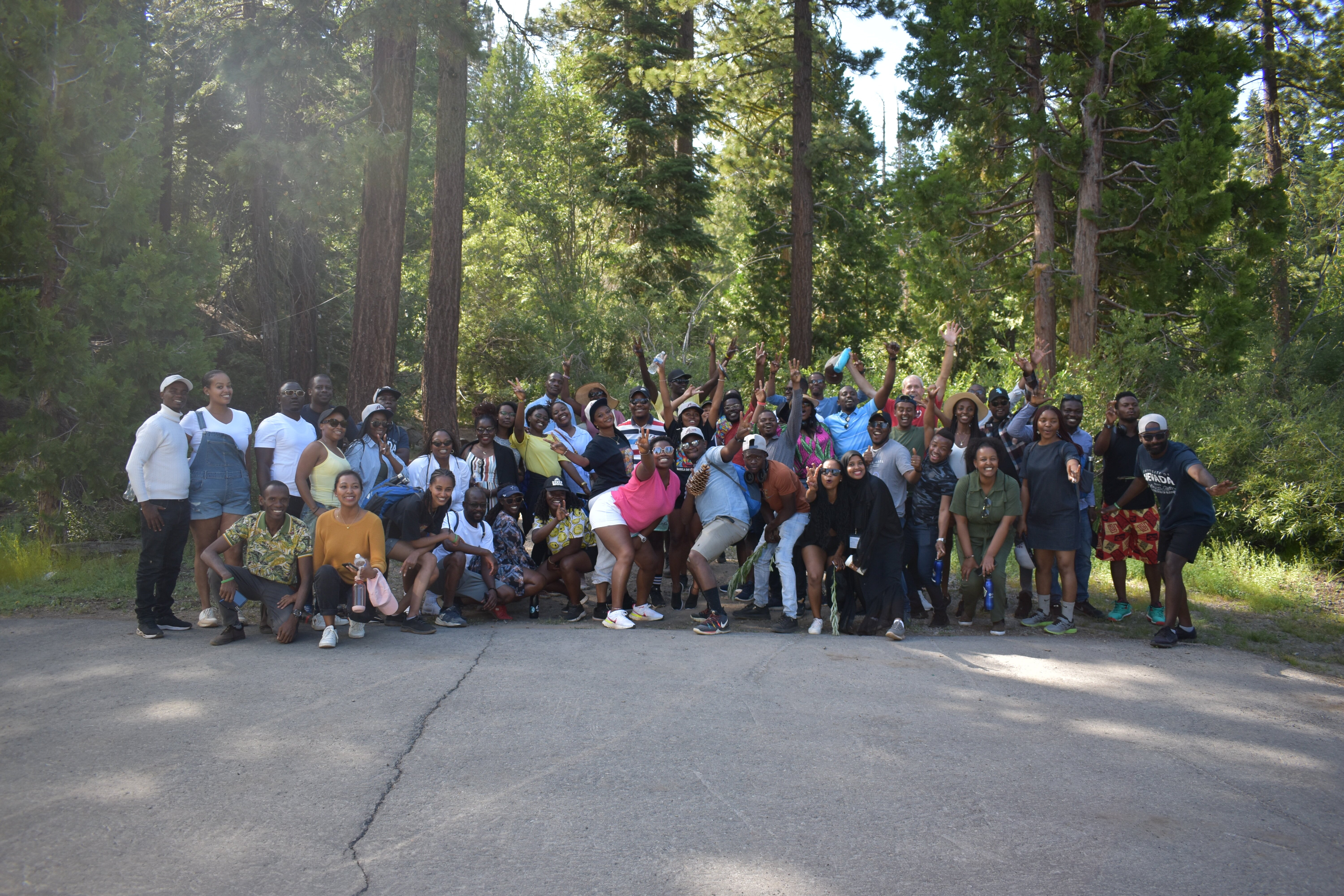 The Fellows smile with their arms up in front of a grove of trees in Tahoe.
