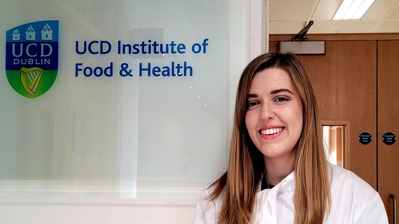 University College Dublin Ph.D. student Róisín O’Sullivan stands in front of a sign of the UCD Institute of Food & Health