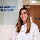 University College Dublin Ph.D. student Róisín O’Sullivan stands in front of a sign of the UCD Institute of Food & Health
